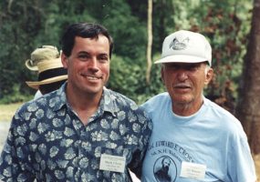 White man smiling in Hawaiian shirt with older white man in T-shirt and hat