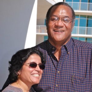 African-American man with glasses and woman with sunglasses smiling on balcony of multistory building