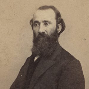 White man with long dark beard in suit and tie