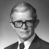 White man with large glasses in suit and tie