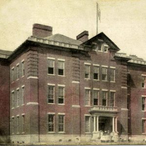 Three story brick building with flagpole on roof, group of women on front steps