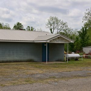 Concrete block building with covered entrance propane tank and metal shed