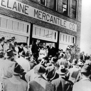 White men in suits talking to a crowd outside the Elaine Mercantile Co.