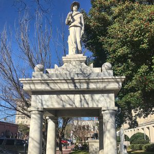 Statue of soldier on top of stone canopy with statue of birds in a well under it