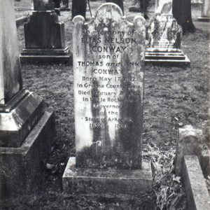 White marble grave marker with stains of age surrounded by other grave markers