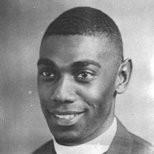 Young African-American man with close-cropped hair in suit with white clerical collar