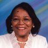 African-American woman with glasses smiling in white top