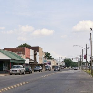 Street with storefront buildings road signs and parked cars