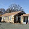 Single-story stone building with covered porch on parking lot