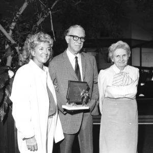 Two white women stand next to a white man holding Arkansas trophy