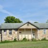 Stone building with covered porch on grass