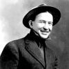 White man smiling in suit and hat