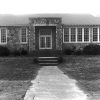 Single-story stone building with covered entrance and sidewalk