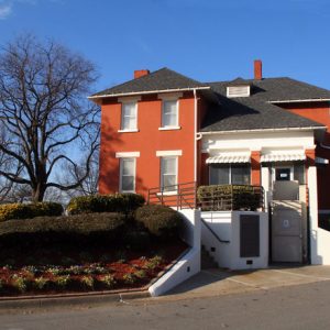 two-story brick building with decorative shrubs and other plants