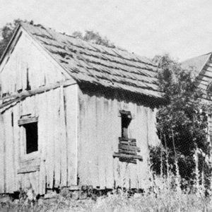 Small dilapidated house with boarded up window