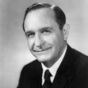 White man with dark hair posing in suit and tie