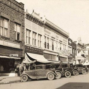 Parked cars on street outside row of brick storefronts