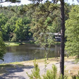 sunny lake and large cabin building as seen from opposite bank