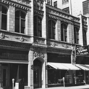 Close-up of multistory storefront building with arched windows and doorway