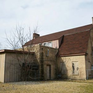 Rear wing of multistory building with gambrel roof with attached shed