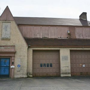 Front view of multistory building with two garage bays and gambrel roof