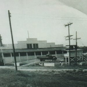 Truck on platform outside single-story building with covered porch