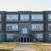 Three-story brick school building with arched entrance and stairs