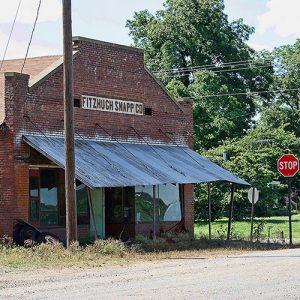 Single-story brick storefront with wood awning and stop sign