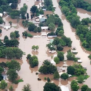 Flooded neighborhood with highway bridge over river in the background