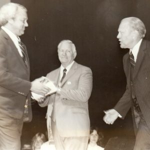 Three white in suits and ties men on stage