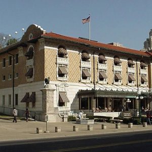 Three-story building with elaborate awning on front and striped awnings on windows on street with Army-Navy hospital in background