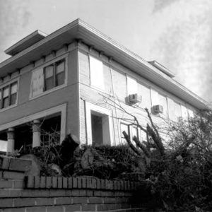 Looking up at front of multistory house with covered porch and two columns