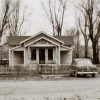 Single-story building on a dirt road with car parked in front