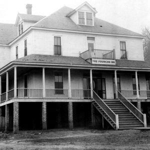 multistory building on brick columns with staircase with sign "the fourche inn"