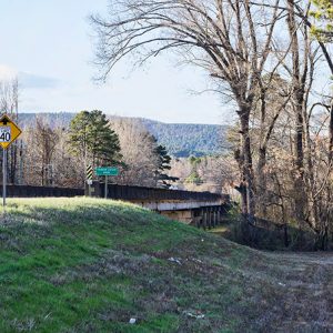 Concrete bridge over river on hillside with road signs