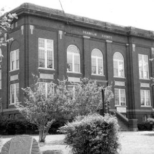 Three-story brick building labeled "Franklin County" with trees in bloom