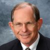 White man with glasses smiling in suit and tie