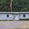 Single-story brick building with flagpole and parking lot