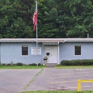 Single-story brick building with flagpole and parking lot