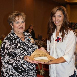 two smiling white women holding a piece of a quilt