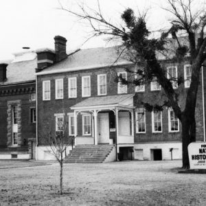 Multistory brick building with front steps chimneys covered entrance connected building "national historic site" sign