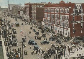 Crowded city street with multistory buildings cars and trolley car