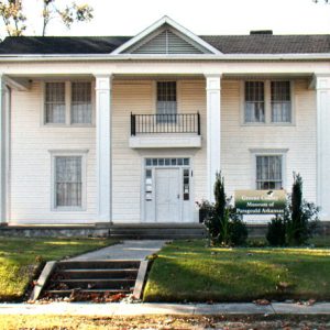 Multistory house with covered porch and sign with sidewalk in the foreground