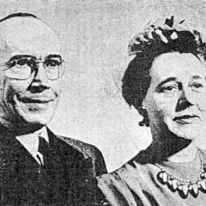 White man in glasses and woman in large necklace smiling