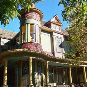 Close-up of ornate multistory house with covered porch and corner tower