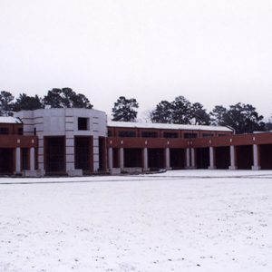 Two-story brick building with open walk ways on snow with a light pole with a spherical fixture