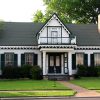 Wood frame two story house ornate triangle pattern roof line  balcony and chimneys on opposite ends with manicured lawn