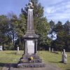 Tall weathered stone monument in cemetery