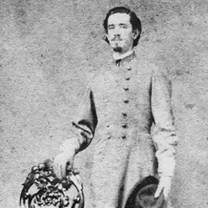 White man standing in gray military uniform with chair and hat