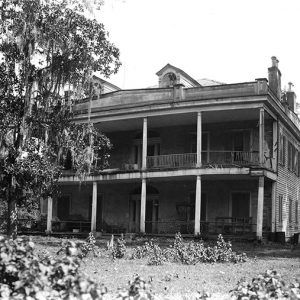 Dilapidated two-story house with covered porch and balcony